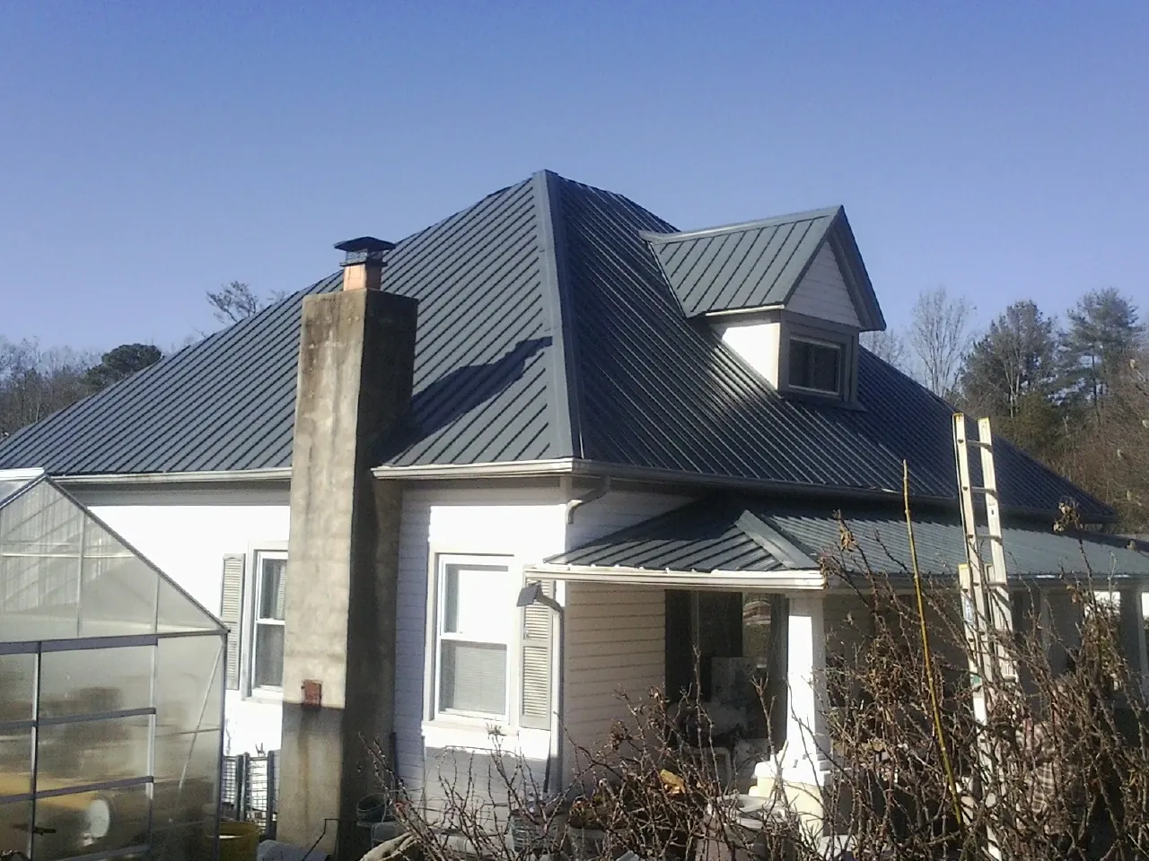 Dark blue standing seam metal roof on a white farmhouse with dormer — Slate & Tile Roof Repair by Roofing Brothers in Stevens Point