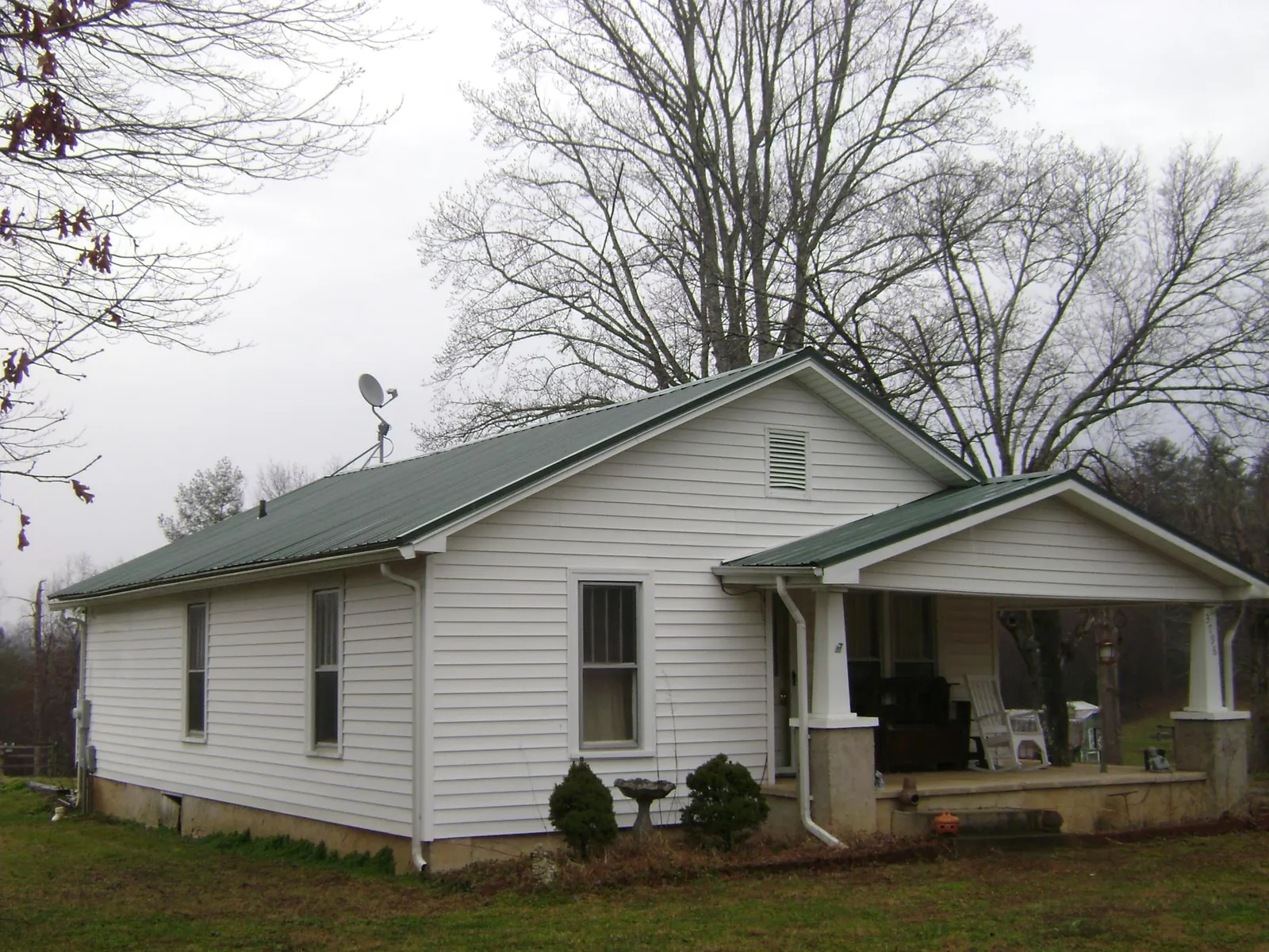 Green metal roof on a white bungalow with a side porch in Stevens Point