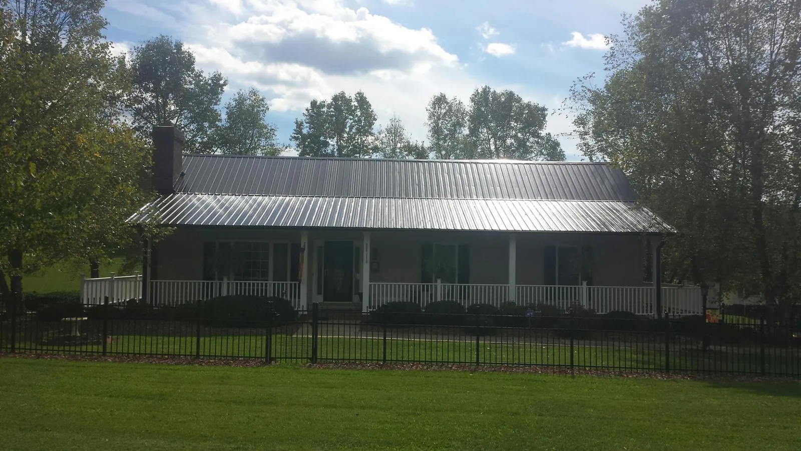 Gray metal roof on a brick ranch with a full width front porch — Gutter Guard Installation work by our crew in Stevens Point