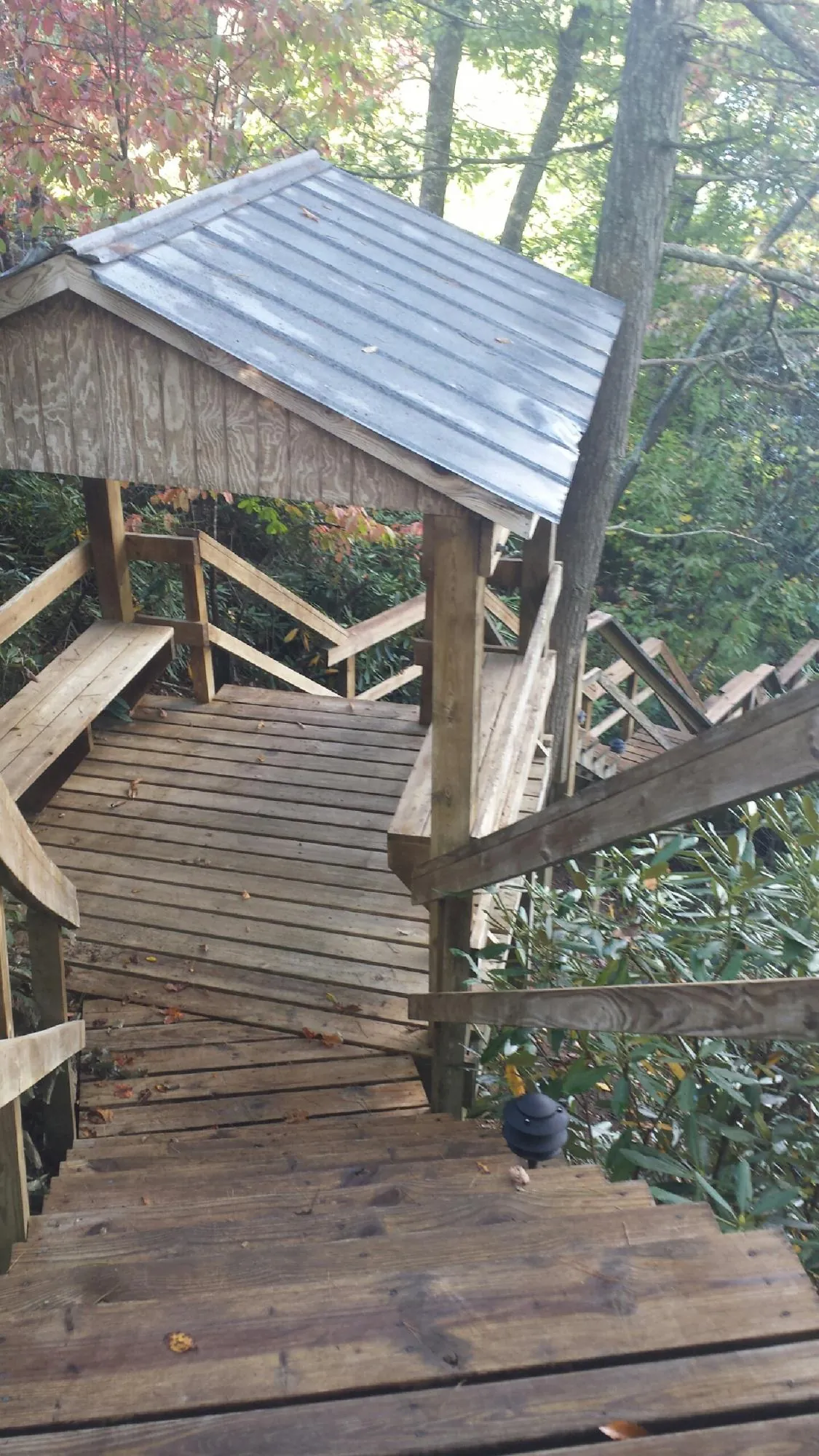 Metal roofed shelter over wooden steps on a wooded walkway — Skylight Repair & Installation work by our crew in Stevens Point