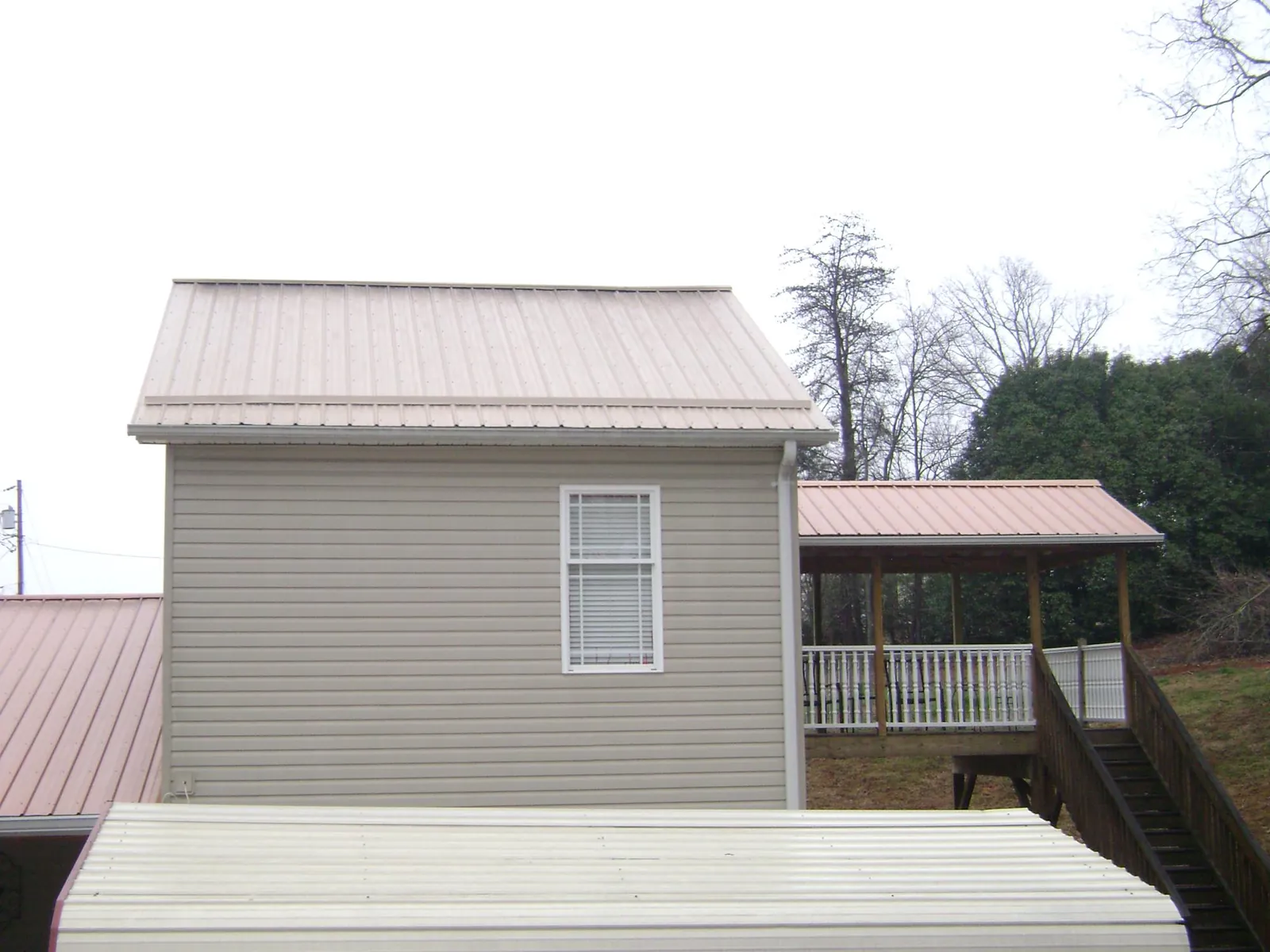 Tan metal roofs on a two story addition and attached porch, from a Roof Replacement job in Stevens Point