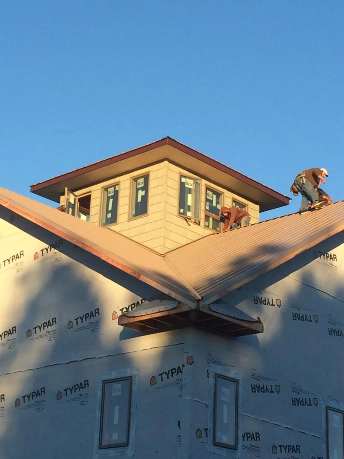 Roofers working around a rooftop cupola on a new metal roof at sunset — Roof Waterproofing in Stevens Point by Roofing Brothers